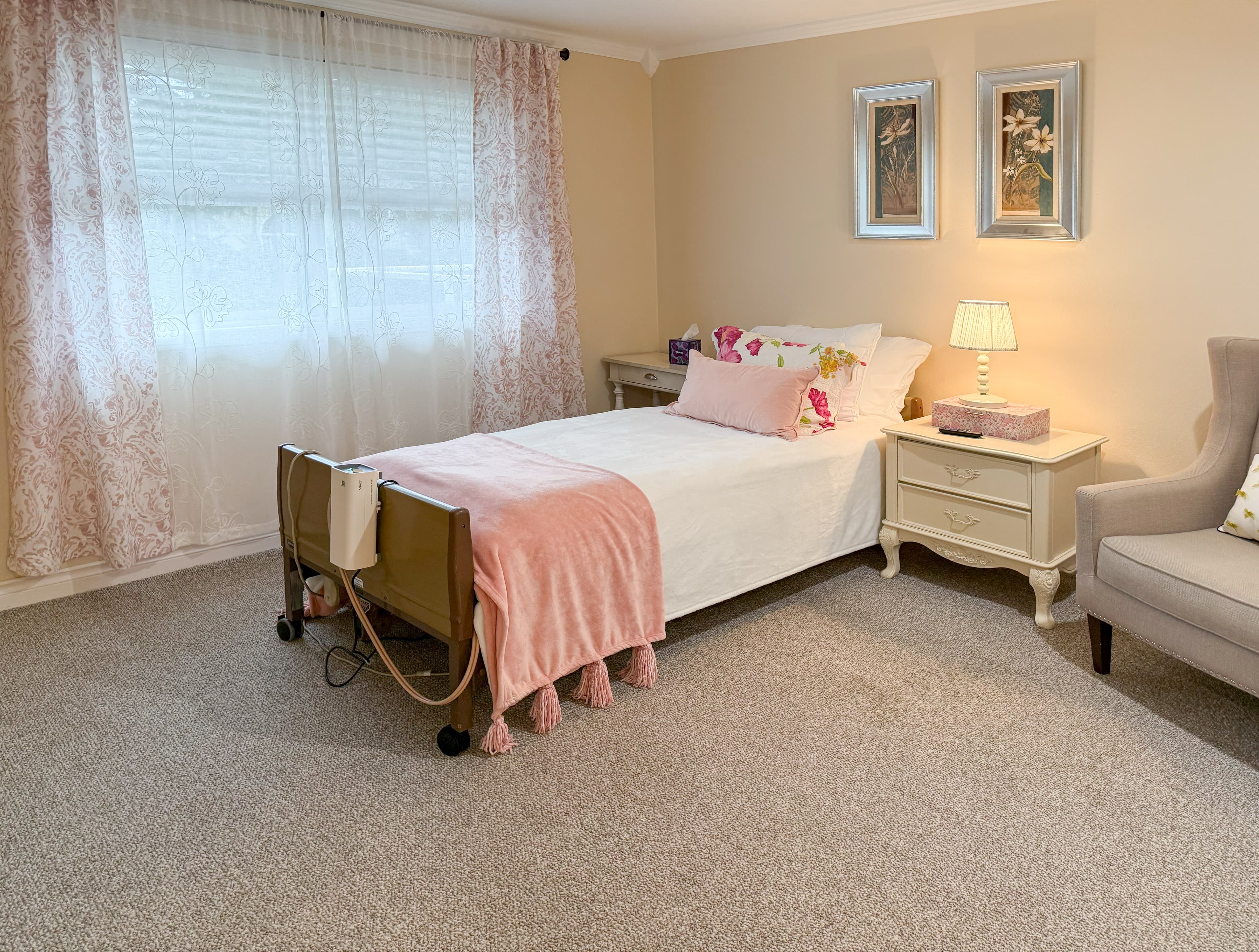 A Brookwood House bedroom with warm bedding, framed artwork, and a wood dresser.