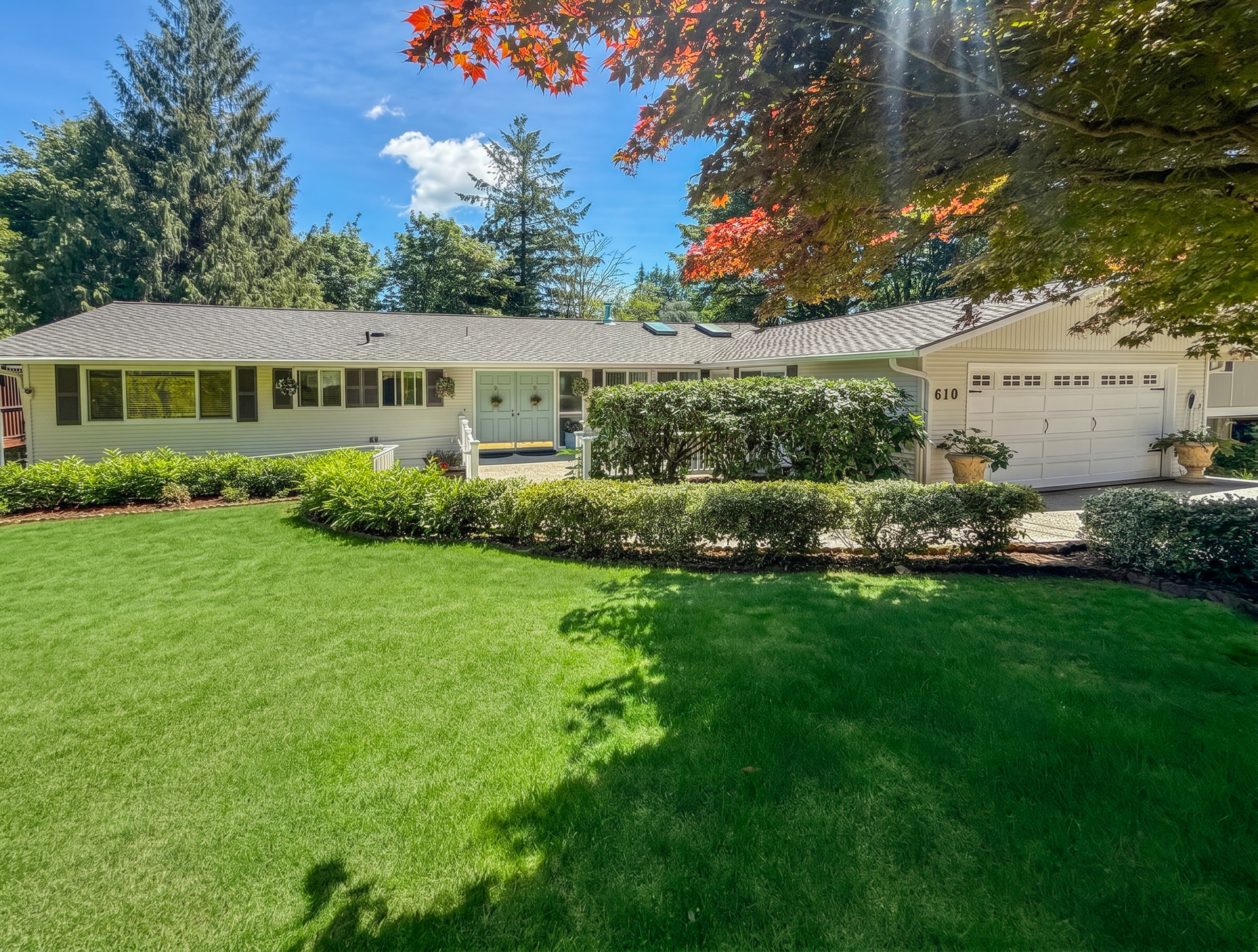 The front of Brookwood House in Bellevue, a single-level residence framed by lawn and trees in autumn light.