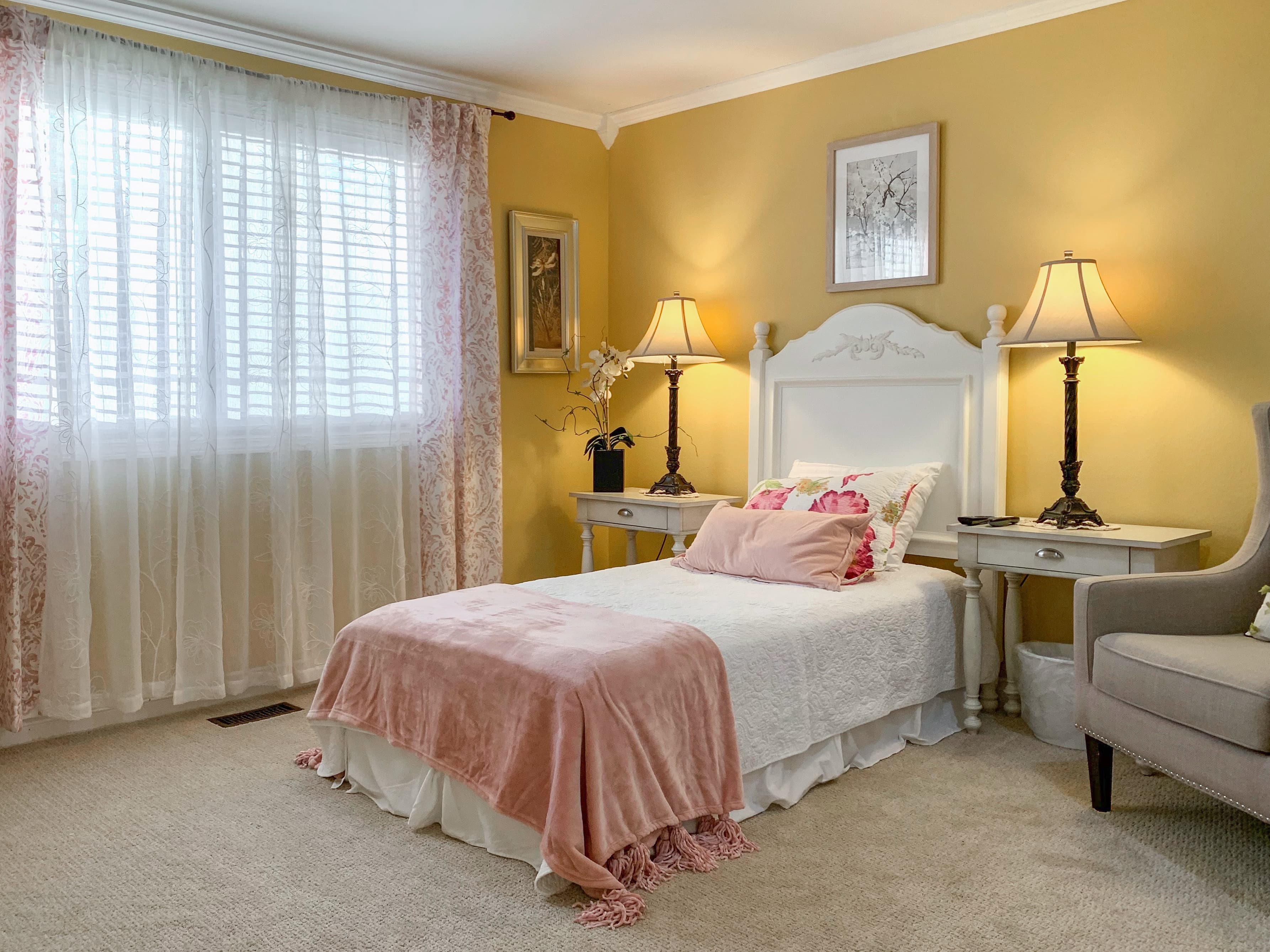 A bedroom at Brookwood House with a nightstand and window-side seating.